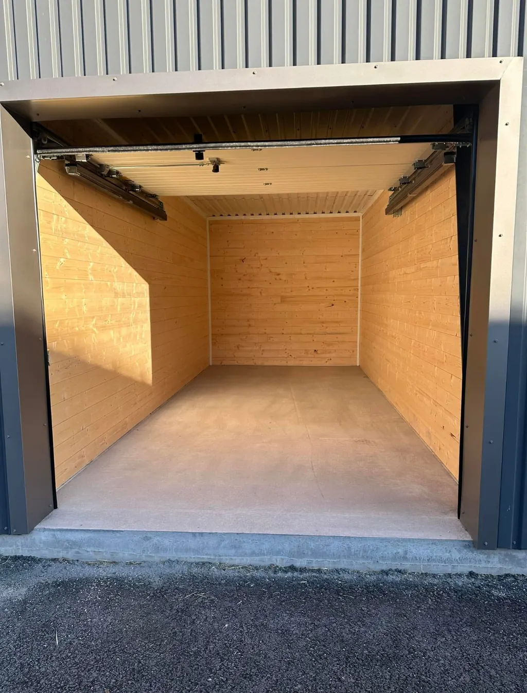 Innsiden av en garasje med lyst trepanel og betonggulv
