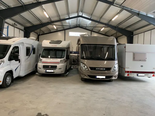 Bobiler og campingvogn parkert i en isolert lagerhall